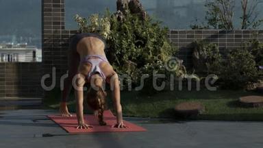 女孩持瑜伽姿势站在露台的凯雷马特
